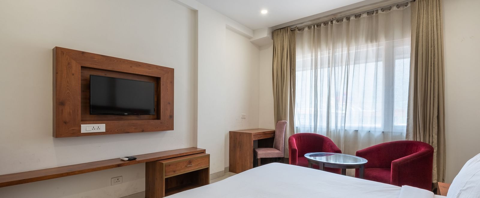 Club balcony room featuring a comfortable bed, wall-mounted TV, and a balcony partially covered by sheer curtains at DLS The Classio